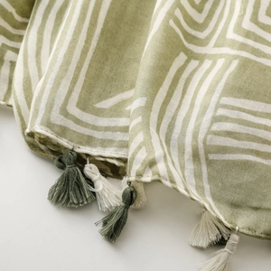 Macro detail of grass green linen-feel scarf with cream lines and tassel fringe detail