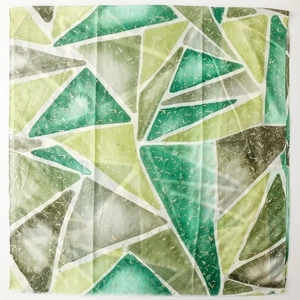 Dettaglio della sciarpa in lino con triangoli geometrici dorati in verde e bianco