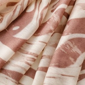Detail of tropical leaf print fabric showing terracotta red and cream twill texture