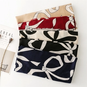 Detail of multi-color bow print linen scarves with fine fringe on a white surface
