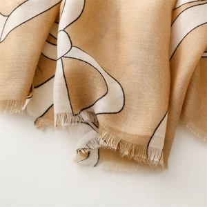 Detailed view of camel scarf with white floral patterns and soft fringe trim edges