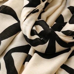 Detailed texture of cotton-linen scarf with black abstract pattern and soft fringe finish