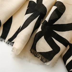 Detail of soft cotton-linen scarf showing black abstract patterns and fringed edges