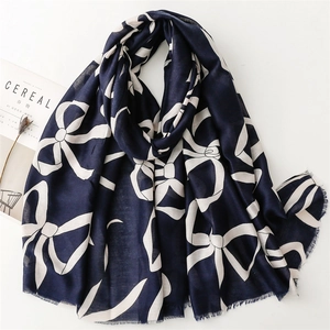 Detail of navy blue cotton linen scarf featuring white bow print and frayed edge design