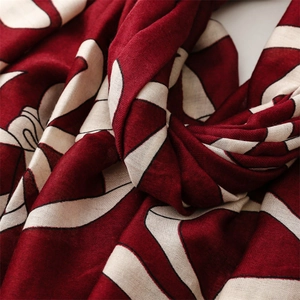 Detailed close-up of soft cotton-linen texture and red abstract patterns on the scarf