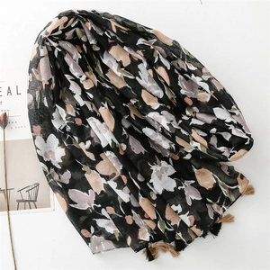 Floral cotton linen scarf with night rose pattern and tassel trim laid flat on a desk