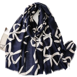 Dark blue linen-feel scarf with large white bow print and frayed edges, flat lay view