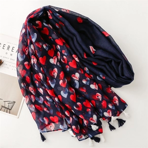 Detail of dark blue scarf with red heart prints and fringe edges on white background