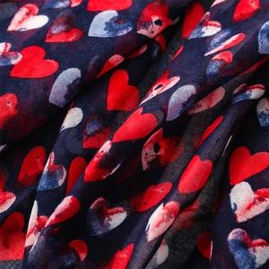 Close-up of soft cotton-linen feel scarf featuring red heart patterns and blue fabric texture