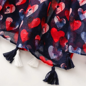 Close-up of lightweight navy blue scarf with red and white heart patterns and fringe trim