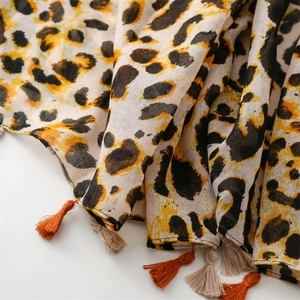 Detailed view of leopard print scarf with cotton-linen texture and orange fringe tassels