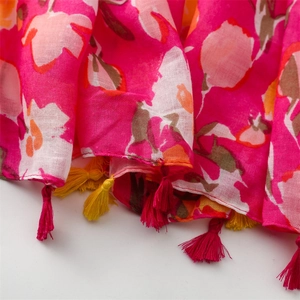 Détail d'écharpe fuchsia à fleurs montrant l'imprimé pensée et les pompons à franges