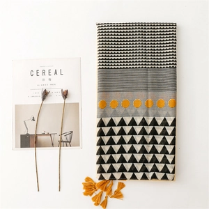 Artistic scarf with geometric patterns and yellow tassels on a lifestyle background