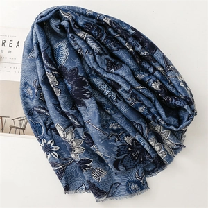 Detail of floral printed scarf featuring intricate blue flower patterns and fringed edges