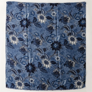 Flat lay of navy blue scarf with light blue floral peonies and fringe detail