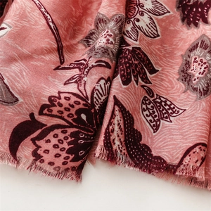 Detailed close-up of pink floral linen scarf featuring purple flower patterns and fringe edges