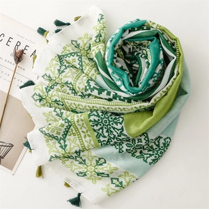 Detail of green bohemian shawl with geometric patterns and fringe tassels