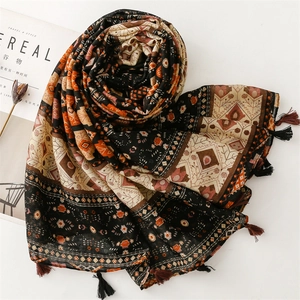 Detail of bohemian geometric print scarf with decorative edge tassels on flat lay surface