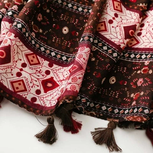Detail of bohemian scarf showing geometric patterns, dark red tones and handmade tassels