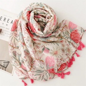Close-up of a cream-colored cotton linen scarf with pink floral prints and fringe details