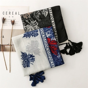 Detail of printed cotton linen scarves with fringe edges and leaf patterns on flat lay