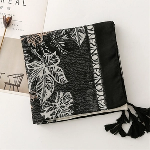 Detail of leaf pattern scarf with black tassels and decorative lettered borders