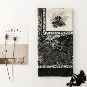 Close-up of black and white leaf print scarf with tassels and minimalist letter design