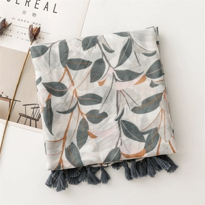Dettaglio sciarpa in cotone e lino con stampe di foglie grigio-blu e nappe grigio scuro