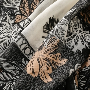 Detailed close-up of cotton-linen feel scarf featuring tropical palm leaf print and texture
