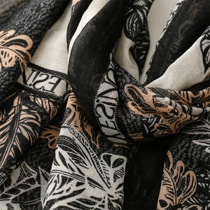 Detail of soft cotton-linen feel scarf featuring tropical leaf prints and decorative letters