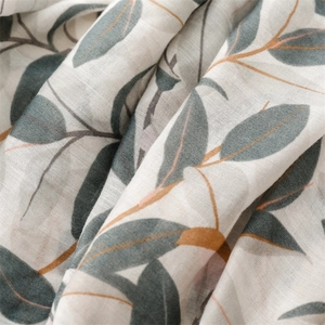 Dettaglio del tessuto effetto lino con stampe di foglie grigio-blu nordiche e nappe