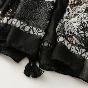 Close-up of black and white palm leaf print scarf with cotton tassel fringe detail