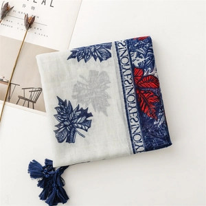 Minimalist layout of linen feel scarf with leaf prints and tassels on white surface