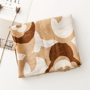 Detail of linen-feel scarf with brown cartoon bear prints and frayed edge craftsmanship