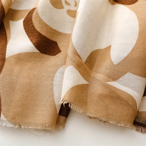 Close-up of khaki camellia floral print on soft cotton-linen scarf with fringed edges