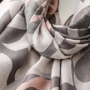 Detail of soft linen-touch scarf featuring elegant khaki floral and geometric patterns