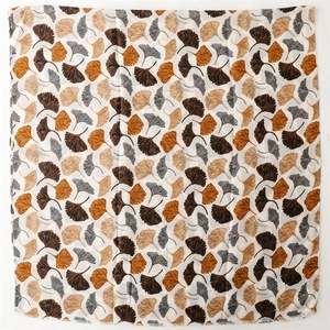 Flat lay of linen-feel scarf featuring autumn ginkgo leaf prints and frayed edges