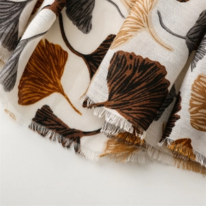 Detail of linen-feel scarf with vintage white ginkgo leaf print and fringe edges