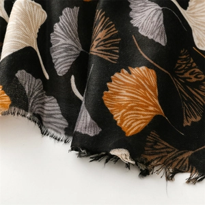 Detail of linen-feel scarf featuring white and orange ginkgo leaf prints with raw edges