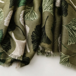 Detail of olive green scarf showing linen texture and ginkgo leaf pattern with frayed edges