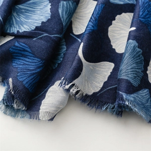 Detail of navy blue cotton linen scarf featuring white ginkgo leaves and fringed edges