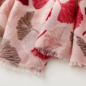 Detailed macro view of pink cotton linen scarf featuring red ginkgo leaf prints and fringe