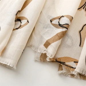 Dettaglio di sciarpa beige in cotone con stampe astratte e bordi sfrangiati delicati