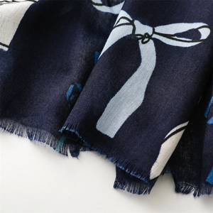 Dettaglio di sciarpa blu scuro con stampe a fiocco azzurre e bordo con frange