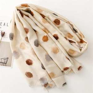 Détail d'une écharpe beige doux avec pois colorés artistiques et bords à franges fins