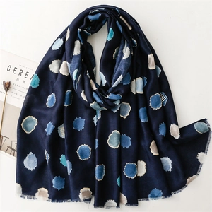 Détail d'une écharpe bleu foncé avec des pois aquarelles et des bords à franges