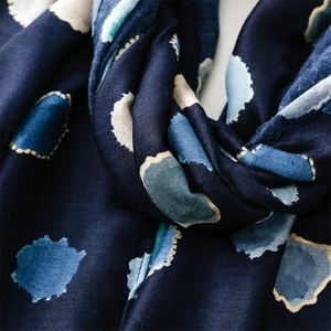 Gros plan sur une écharpe bleu marine avec pois dorés et texture satinée douce