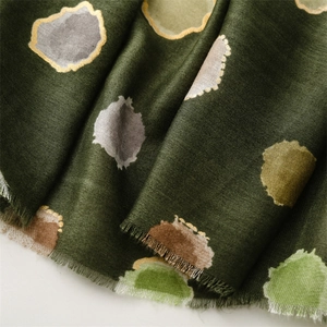 Détail d'une écharpe vert foncé avec pois colorés et bordures à fines franges