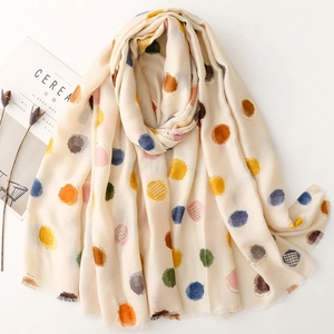 Détail d'une écharpe beige avec pois multicolores et bordure élégante en feuille d'or