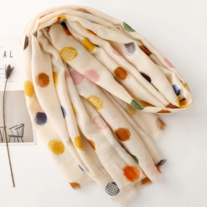 Gros plan d'une écharpe beige avec pois colorés et bordures à franges douces